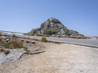 a lone bicycle is parked at the edge of an open road near a cliff by the sea