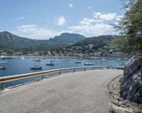 a paved road beside some large boats and a bridge with a bridge to the water