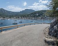 a paved road beside some large boats and a bridge with a bridge to the water