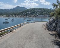 a paved road beside some large boats and a bridge with a bridge to the water