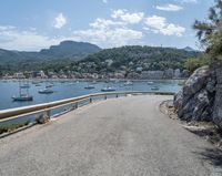 a paved road beside some large boats and a bridge with a bridge to the water