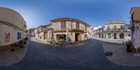 an image taken from 360 - angle in a city with buildings and tables on the sidewalk