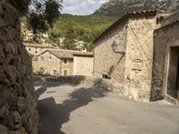 there are two buildings in this town, with stone walls and trees on top of the hillside