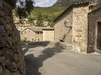 there are two buildings in this town, with stone walls and trees on top of the hillside