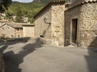 there are two buildings in this town, with stone walls and trees on top of the hillside