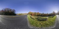 a split - open road that has a fence and green grass on both sides,