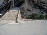 stairs going up to the side of a steep hill in a cliff type area with a white bicycle