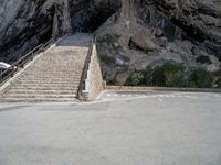 stairs going up to the side of a steep hill in a cliff type area with a white bicycle