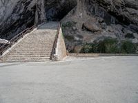 stairs going up to the side of a steep hill in a cliff type area with a white bicycle