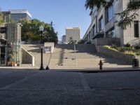 a lot of stairs next to a building with trees in the background - and a red fire hydrant at the bottom of one