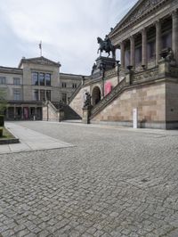 a statue sits in the center of a courtyard in front of a building with a statue on the side