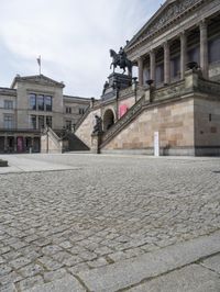 a statue sits in the center of a courtyard in front of a building with a statue on the side