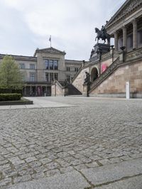 a statue sits in the center of a courtyard in front of a building with a statue on the side