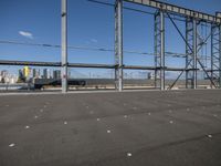 a view of a steel frame and a train in the distance from an airport parking lot