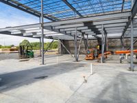 a garage that has concrete floors and steel roofing in it and a forklift on the ground