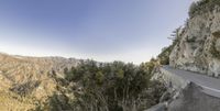 a steep, winding road near trees on a cliff side trail near mountains and mountains