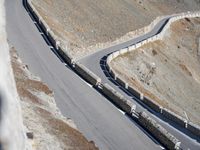 a lone motor bike is traveling down the road near a curve and stones wall beside the winding roads