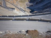 the bike rider is riding down the steep slope of a mountain road towards a valley