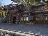 stone bench in front of a long building with many chinese decor on it, with a building behind