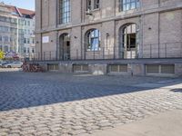 the sidewalk in front of a large stone building on a sunny day with sun shining on it