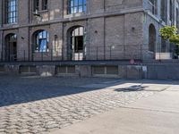 the sidewalk in front of a large stone building on a sunny day with sun shining on it