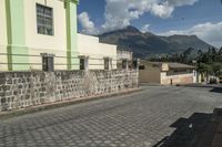 a stone walkway going down to a stone building next to a tall building with mountains in the background