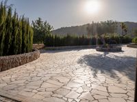 a stone fence sits near a stone building and gate in the country setting of a greek property