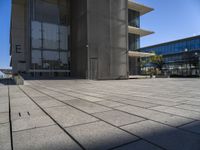 a stone floor outside of a building with buildings in the background and a bench at the end