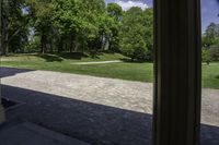 a stone path between a wooded area and trees and a park in the background with columns