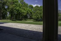 a stone path between a wooded area and trees and a park in the background with columns