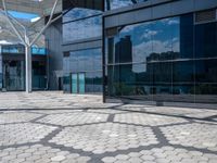 a stone path with small white circles in the middle next to a building in front of large glass windows