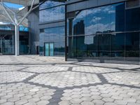 a stone path with small white circles in the middle next to a building in front of large glass windows