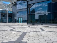 a stone path with small white circles in the middle next to a building in front of large glass windows