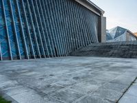 a stone pathway outside a modern building that is blue in color, looking up at the ground and sky