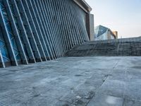 a stone pathway outside a modern building that is blue in color, looking up at the ground and sky