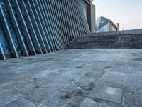 a stone pathway outside a modern building that is blue in color, looking up at the ground and sky