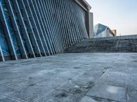 a stone pathway outside a modern building that is blue in color, looking up at the ground and sky
