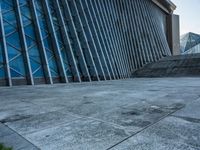 a stone pathway outside a modern building that is blue in color, looking up at the ground and sky