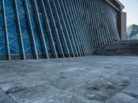 a stone pathway outside a modern building that is blue in color, looking up at the ground and sky