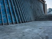 a stone pathway outside a modern building that is blue in color, looking up at the ground and sky