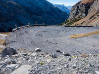 a stone road curves into the mountainside in the austrian alps, with two yellow traffic cones