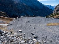 a stone road curves into the mountainside in the austrian alps, with two yellow traffic cones