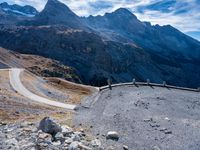 a stone road curves into the mountainside in the austrian alps, with two yellow traffic cones