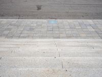 a street with some stone steps and a blue tiled walkway in front of it that has a blue plate on the pavement