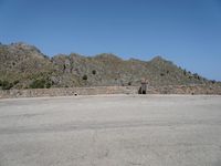 a stone structure stands with mountains in the background and a clear sky overhead is blue