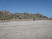 a stone structure stands with mountains in the background and a clear sky overhead is blue