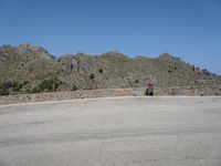 a stone structure stands with mountains in the background and a clear sky overhead is blue