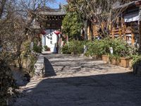 a paved walkway with a stone pathway leading to a building that has red lanterns in it