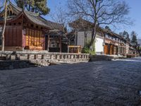 a stone walkway in front of a building with a few wooden benches underneath it,