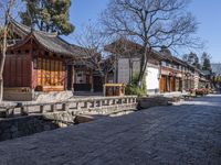 a stone walkway in front of a building with a few wooden benches underneath it,